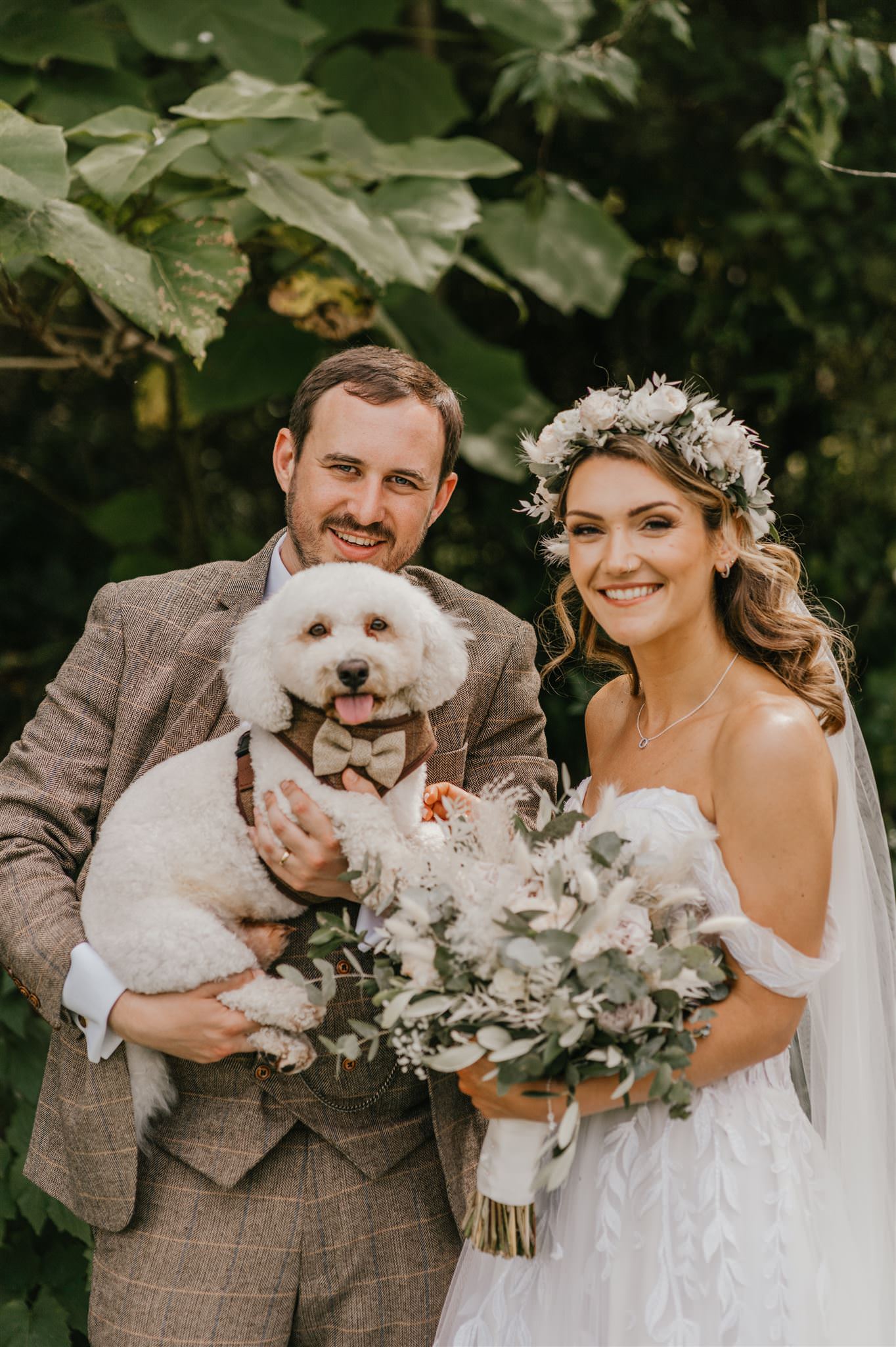 Groom holding Bailey the Bichon Frise at wedding with bride